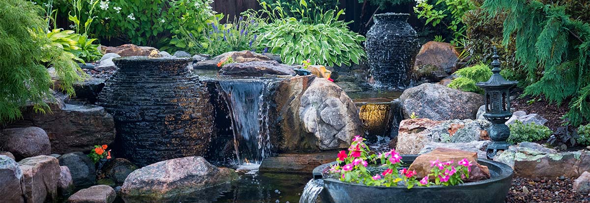 Decorative fountains on display in a beautiful sunny and green backyard. 